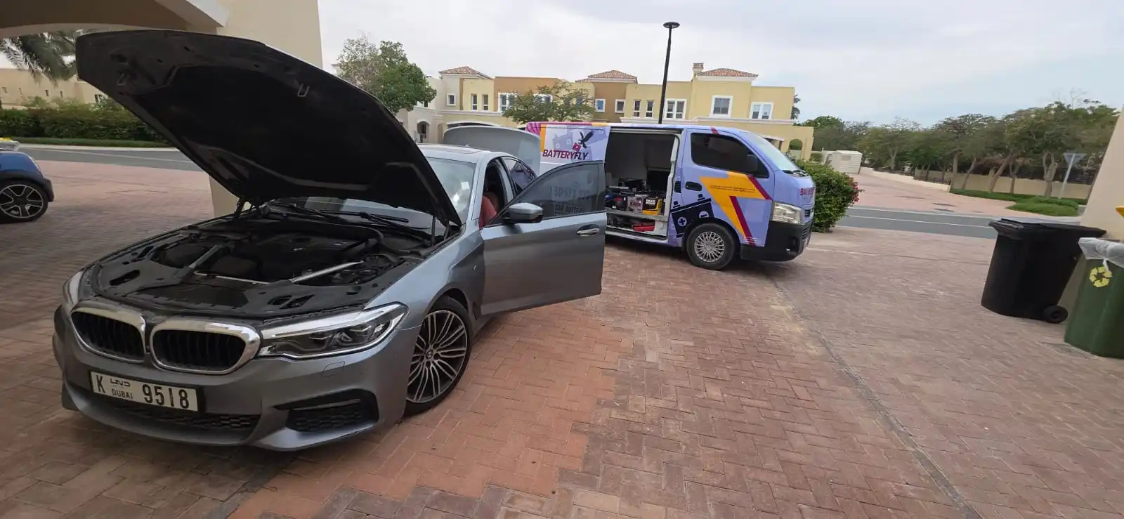 Batteryfly service van beside a BMW with its bonnet open in Dubai.